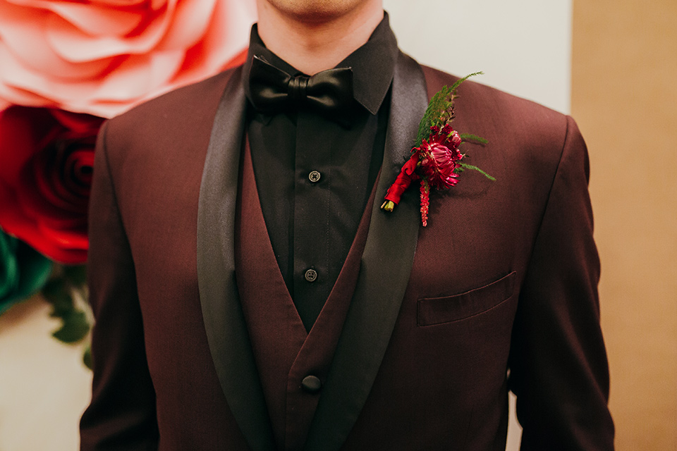 dia-de-los-muertos-shoot-close-up-on-groo-attire-burgundy-tuxedo-with-black-trim-a-black-shirt-and-a-faux-black-bow-tie