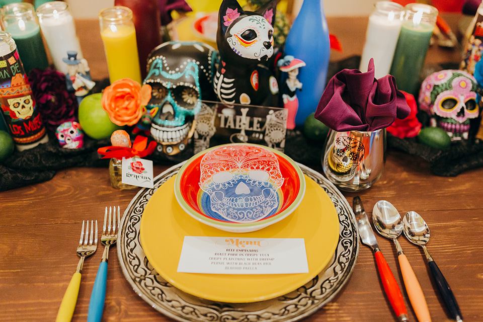 dia-de-los-muertos-shoot-table-decor-close-up-on-candles-yellow-plates-with-sugar-skull-details-color-décor-and-silverware