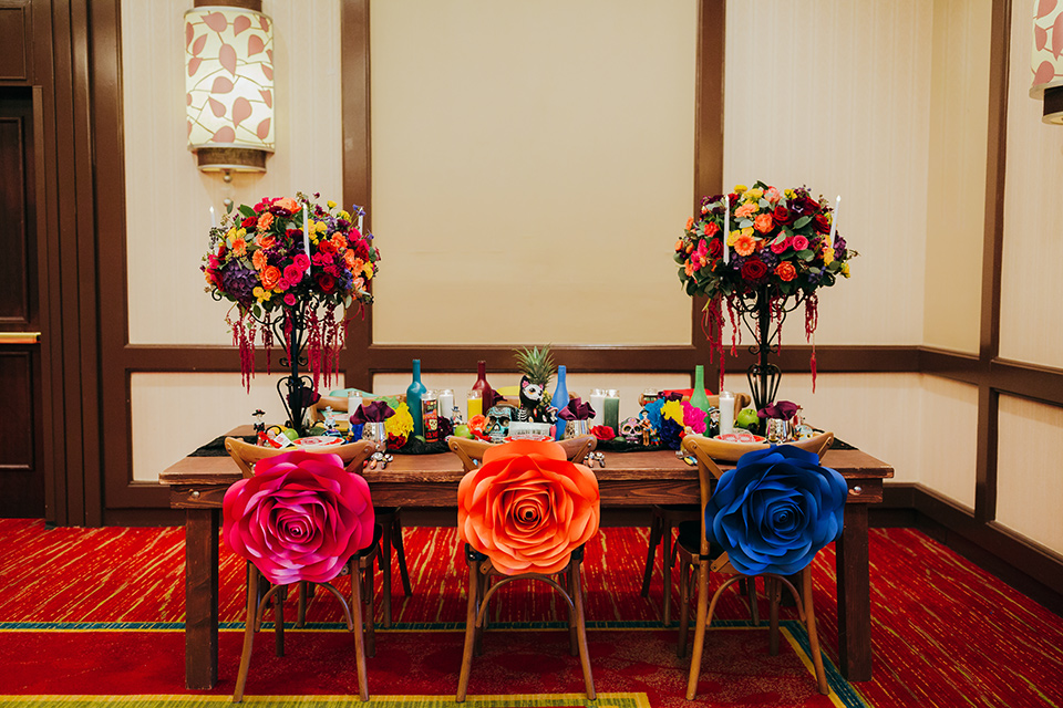 dia-de-los-muertos-shoot-table-set-up-table-decore-close-up-on-little-bottles-table-decor-close-up-on-candles-yellow-plates-with-sugar-skull-details-color-décor-and-silverware-gold-chairs-and-table-accents