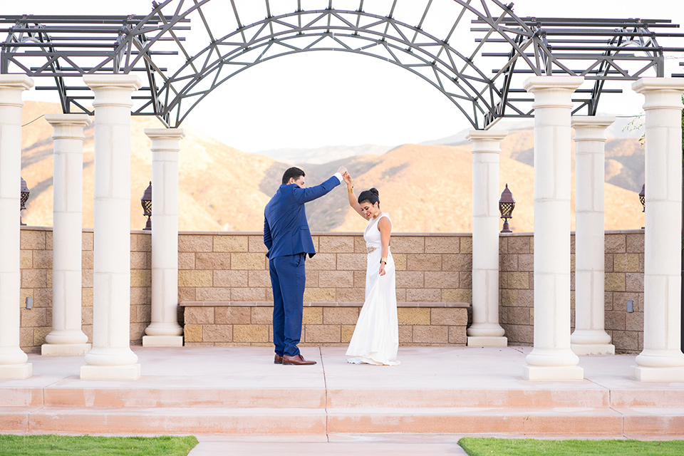 wonder-woman-meets-superman-dancing-bride-in-a-white-silk-dress-with-her-wonder-woman-head-piece-while-groom-is-in-a-white-dress-shirt-with-a-red-tie-and-red-cape-and-blue-pants