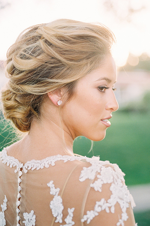 Inn-at-rancho-santa-fe-shoot-bride-close-up-focus-on-hair-bride-in-a-lace-gown-with-an-illusion-detailing-with-a-nude-underlay-with-her-hair-in-back-in-a-loose-bun