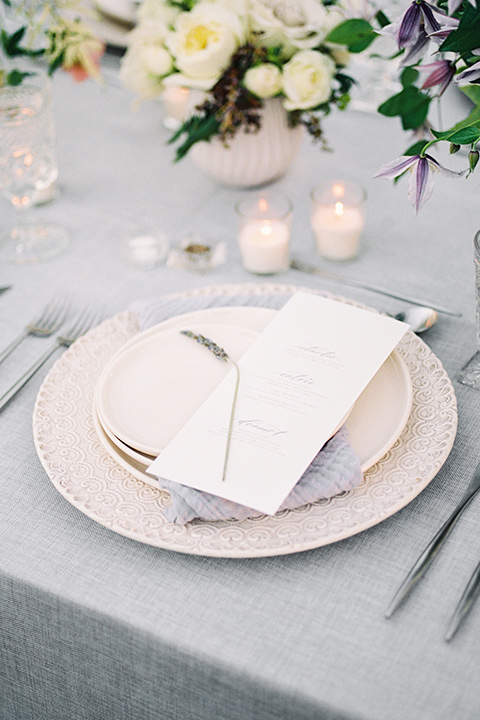 Inn-at-rancho-santa-fe-shoot-close-up-on-table-décor-white-plates-with-silver-chargers-with-mitallic-silverware-with-flowers-all-around