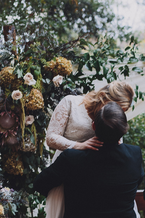 amanda-and-codys-wedding-at-the-1909-groom-picking-up-bride-and-kissing-her-bride-in-an-a-line-dress-with-a-tulle-skirt-and-lace-long-sleeve-bodice-groom-in-all-black-shawl-lapel-tuxedo