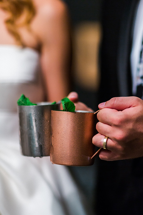 Childrens-museum-shoot-cocktails-bride-sitting-in-chair-groom-standing-looking-at-each-other-bride-in-a-white-modern-strapless-ball-gown-and-groom-in-a-black-tuxedo-with-a-floral-tie