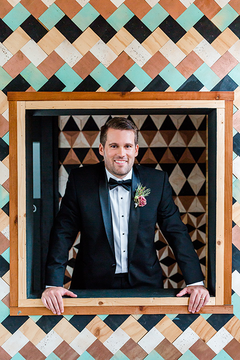 Childrens-museum-shoot-groom-in-window-groom-in-a-black-tuxedo-with-a-floral-tie