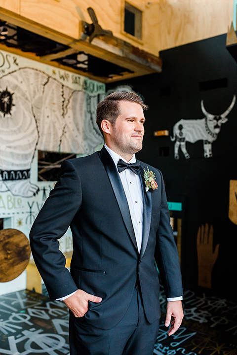 Childrens-museum-shoot-groom-looking-away-from-camera-hand-in-pocket-black-tuxedo-with-a-floral-tie