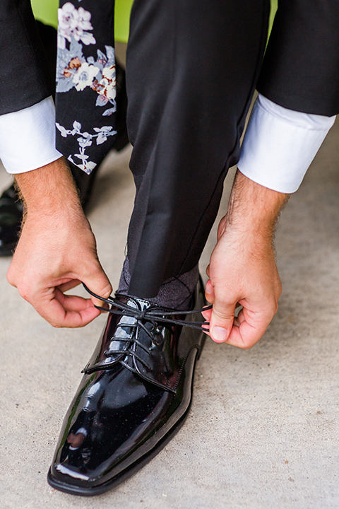 Childrens-museum-shoot-groom-tying-shoes-black-tuxedo-with-a-floral-tie
