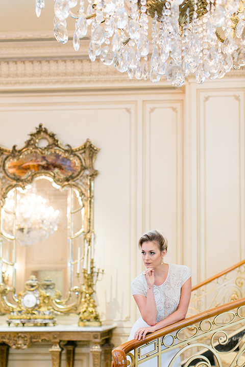 Exquisite-weddings-magazine-bride-leaning-on-staircase-bride-in-a-white-long-sleeved-dress-with-a-plunging-neckline-and-hair-in-a-bun