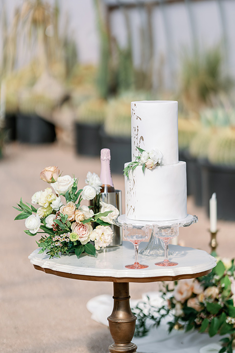 a garden romance wedding inspo with the bride in a luxe lace gown and the groom in a tan suit - cutting the cake 