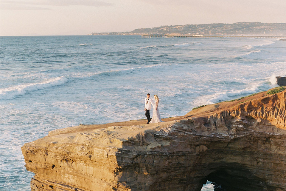  luxe black and white wedding on the beach in san diego – bride in a light blue gown and the groom in a white and black shawl tuxedo 