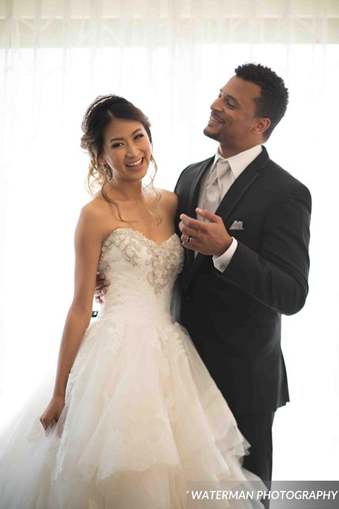 Classic glamour wedding shoot at the avenue of the arts hotel bride strapless ball gown with beaded detail on top with sweetheart neckline and groom black tuxedo with white dress shirt and long silver tie with matching vest and pocket square hugging and smiling