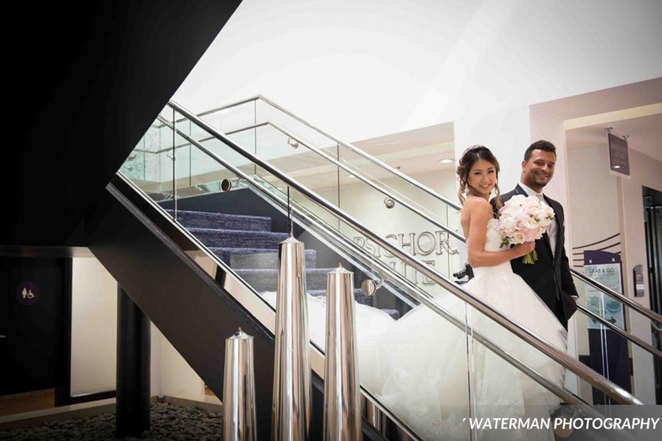 Classic glamour wedding shoot at the avenue of the arts hotel bride strapless ball gown with beaded detail on top with sweetheart neckline and groom black tuxedo with white dress shirt and long silver tie with matching vest and pocket square walking down stairs