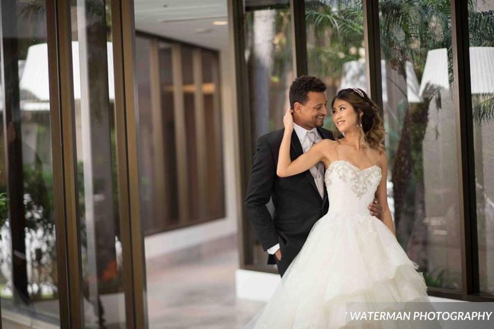 Classic glamour wedding shoot at the avenue of the arts hotel bride strapless ball gown with beaded detail on top with sweetheart neckline and groom black tuxedo with white dress shirt and long silver tie with matching vest and pocket square hugging