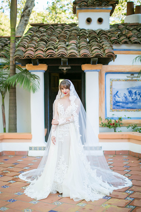 Rancho las lomas spanish inspired wedding shoot bride form fitting strapless lace gown with sweetheart neckline and long veil with lace trim and crystal belt 