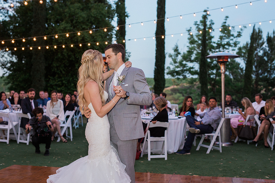 Temecula outdoor wedding at falkner winery bride mermaid style gown with lace bodice and sweetheart neckline with ruffled skirt and long veil with groom heather grey suit with white dress shirt and long white tie with matching pocket square and white floral boutonniere first dance