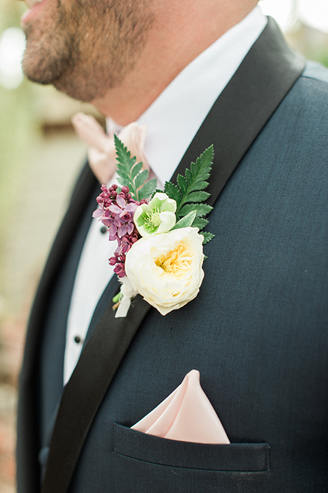 Orange county outdoor wedding shoot at sherman library and gardens groom navy blue shawl lapel tuxedo with matching vest and white dress shirt with blush pink bow tie and pocket square with white floral boutonniere close up