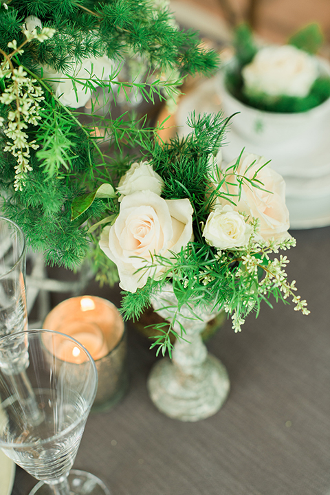 Orange county outdoor wedding shoot at sherman library and gardens table set up with light grey table linen and white place settings with green and white flower centerpiece decor with gold silverware and light brown and white wood chairs