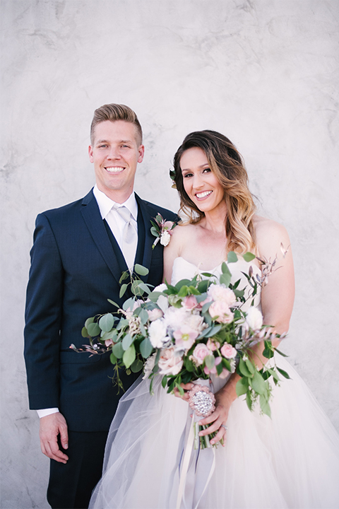 Orange county outdoor wedding at old ranch country club bride strapless ballgown with a sweetheart neckline and beaded detail with groom navy notch lapel suit with matching vest and white dress shirt with long silver tie and white floral boutonniere hugging