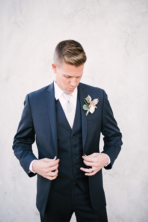 Orange county outdoor wedding shoot at old ranch country club groom navy blue notch lapel suit with matching vest and white dress shirt with long silver tie and white floral boutonniere standing and holding jacket