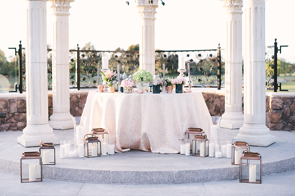 Orange county outdoor wedding shoot at old ranch country club table set up light silver table linen with white and grey place settings with navy blue napkin linen decor with clear wine glasses and dark blue designed glasses with light pink flower centerpiece decor with candles