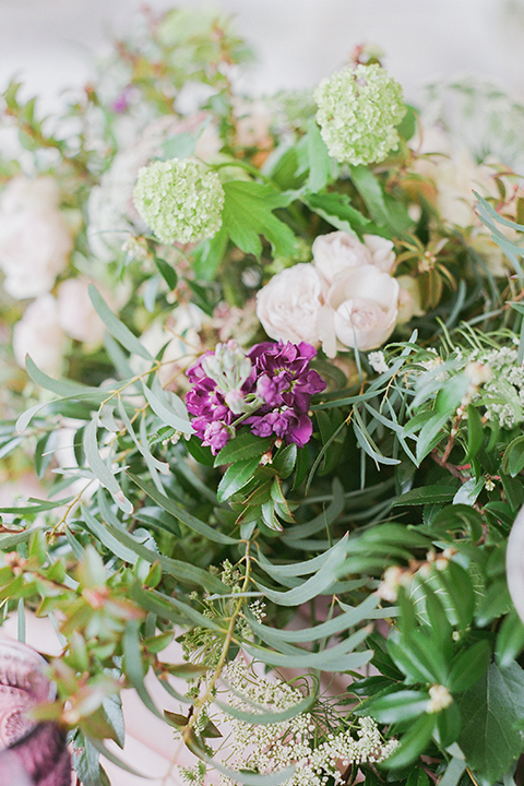 Temecula outdoor wedding at callaway winery table set up light brown wood table with blush pink table runner and white and green flower centerpiece decor with white and gold place settings with blush pink napkins and white and brown vintage chairs