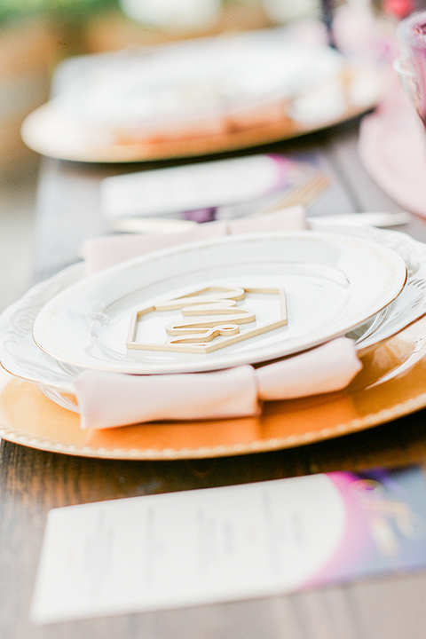 Temecula outdoor wedding at callaway winery table set up light brown wood table with blush pink table runner and white and green flower centerpiece decor with white and gold place settings with blush pink napkins and white and brown vintage chairs