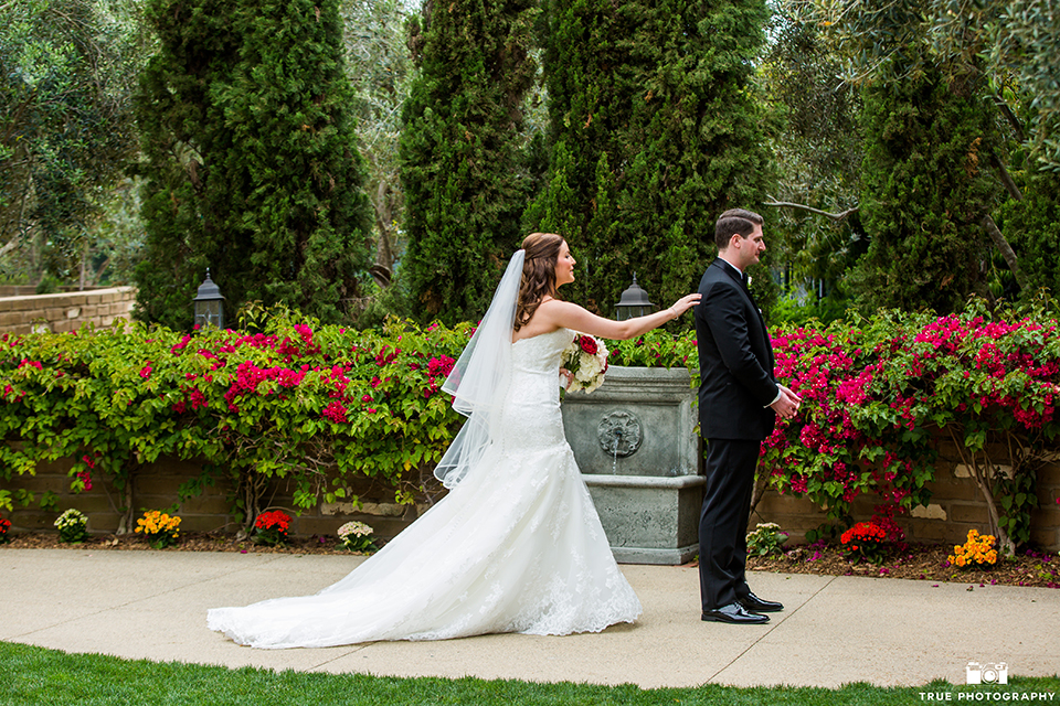 San diego beach wedding at estancia la jolla bride form fitting strapless gown with sweetheart neckline and lace design with long veil and groom black shawl lapel tuxedo with matching vest and white dress shirt with black bow tie and white pocket square with white floral boutonniere first look