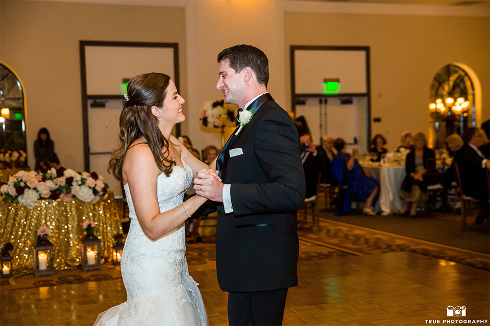 San diego beach wedding at estancia la jolla bride form fitting strapless gown with sweetheart neckline and lace design with long veil and groom black shawl lapel tuxedo with matching vest and white dress shirt with black bow tie and white pocket square with white floral boutonniere first dance