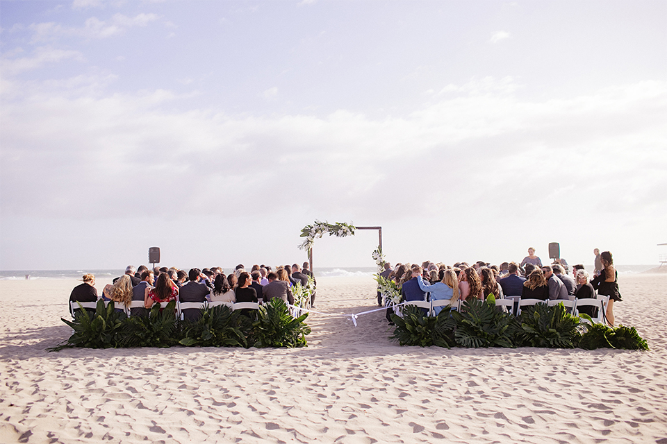 Huntington beach wedding at the hilton waterfront resort wedding ceremony altar with brown wood and white and green flower decor on sand wedding photo idea for ceremony altar with guests sitting in chairs for ceremony