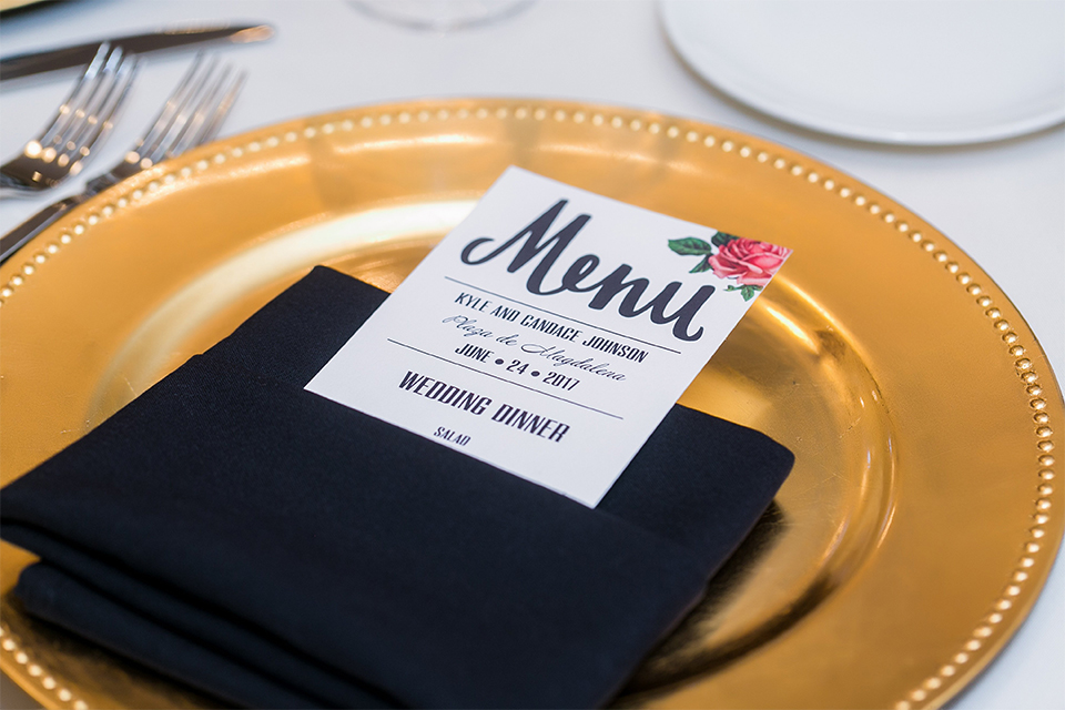 San juan capistrano outdoor wedding at the plaza de magdelena table set up black and white table linen with gold place settings and black linen napkins with white and black calligraphy menu with flower decor and glassware with white and pink flower centerpiece decor and black and white chiavari chairs