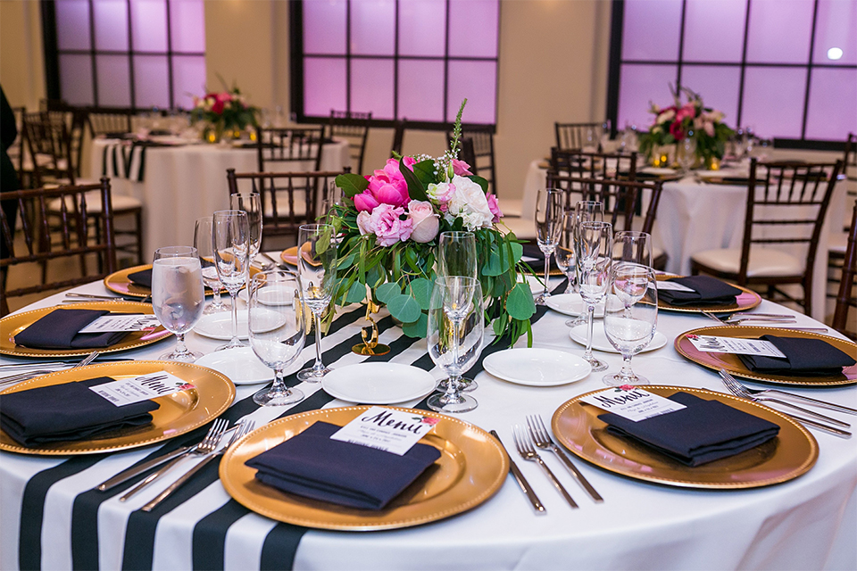 San juan capistrano outdoor wedding at the plaza de magdelena table set up black and white table linen with gold place settings and black linen napkins with white and black calligraphy menu with flower decor and glassware with white and pink flower centerpiece decor and black and white chiavari chairs