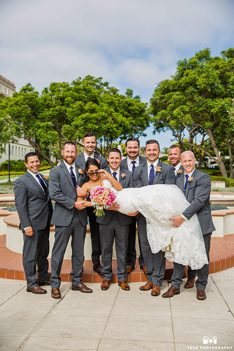 skybox-venue-wedding-bride-with-groomsmen-bride-in-strapless-gown-with-beaded-bodice-groom-in-light-grey-suit-with-ivory-tie-groomsmen-in-dark-grey-sutis