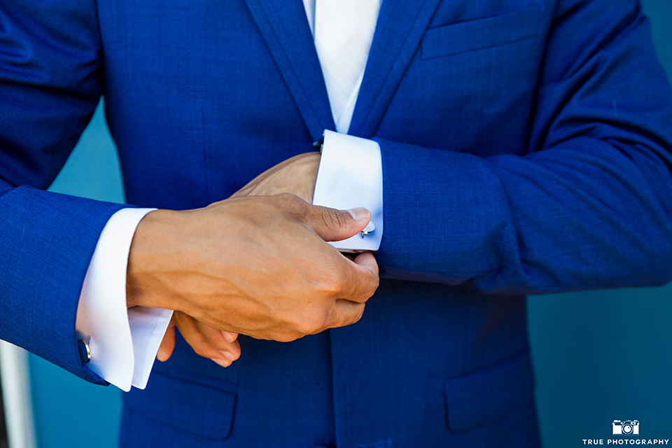 San diego outdoor wedding shoot at bali hai groom cobalt blue notch lapel suit with a white dress shirt and white vest with a long white striped tie and pocket square close up holding sleeve