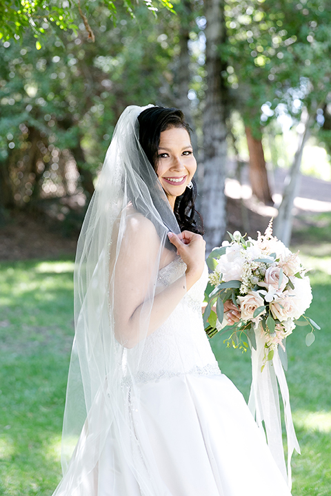 Temecula outdoor wedding at lake oak meadows bride a line strapless gown with lace and detail beading on bodice and long veil holding white and green floral bridal bouquet