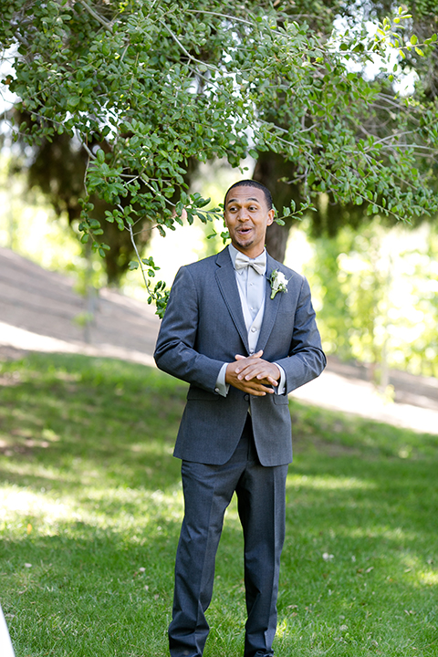 Temecula outdoor wedding at lake oak meadows groom grey notch lapel suit with light grey vest and light grey matching bow tie with white dress shirt and white floral boutonniere smiling