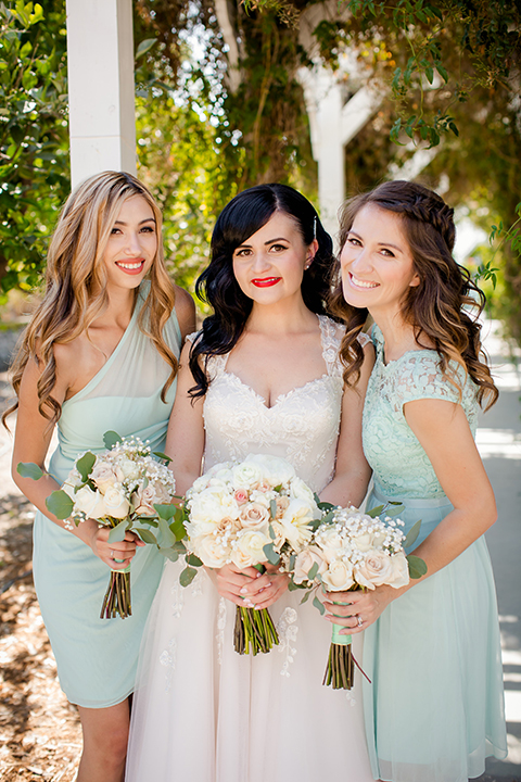 Orange county outdoor summer wedding at the heritage museum bride ball gown with lace straps and a sweetheart neckline with a short tulle skirt and long veil holding white floral bridal bouquet with bridesmaids short mint green dresses holding white floral bouquets