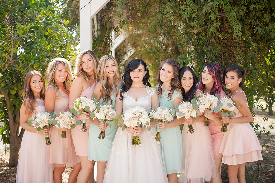 Orange county outdoor summer wedding at the heritage museum bride ball gown with lace straps and a sweetheart neckline with a short tulle skirt and long veil holding white floral bridal bouquet standing with bridesmaids short blush pink and mint green dresses holding white floral bouquets