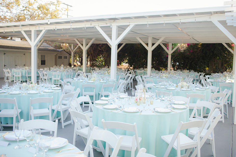 Orange county outdoor summer wedding at the heritage museum table set up with mint green table linens and white chairs with white flower centerpiece decor with glassware and white place settings with gold silverware and candles