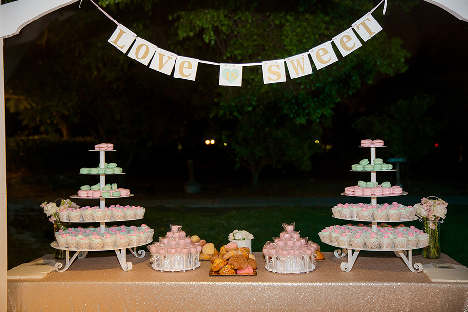 Orange county outdoor summer wedding at the heritage museum table set up with mint green table linens and white chairs with white flower centerpiece decor with glassware and white place settings with gold silverware and candles dessert table with assortment of sweets macarons cake pops and desserts