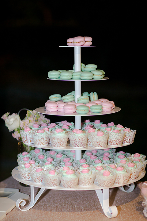 Orange county outdoor summer wedding at the heritage museum table set up with mint green table linens and white chairs with white flower centerpiece decor with glassware and white place settings with gold silverware and candles dessert table with assortment of sweets macarons cake pops and desserts