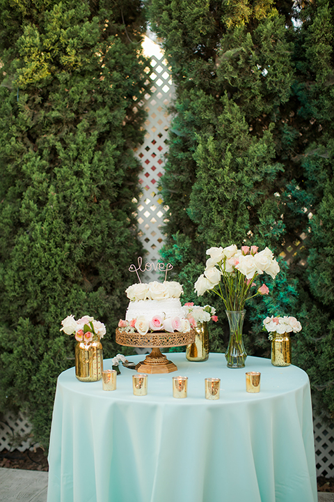 Orange county outdoor summer wedding at the heritage museum table set up with mint green table linens and white chairs with white flower centerpiece decor with glassware and white place settings with gold silverware and candles dessert table with assortment of sweets macarons cake pops and desserts