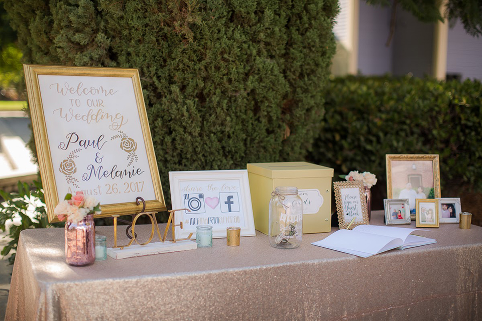 Orange county outdoor summer wedding at the heritage museum wedding welcome sign with white sign and gold frame with gold cursive writing on stand wedding photo idea for ceremony decor on table with card box and gifts