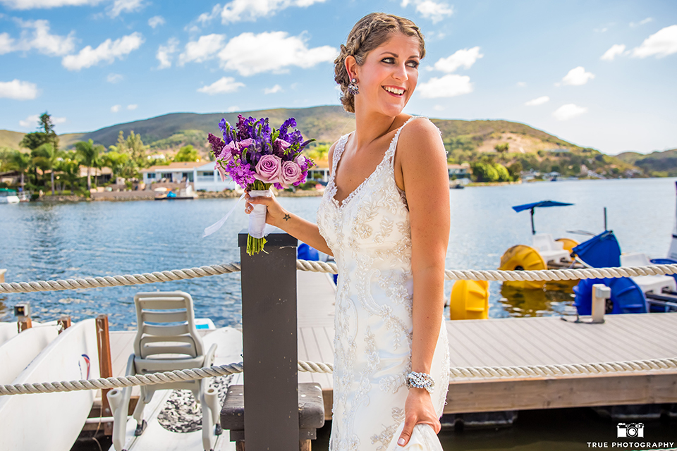 San diego outdoor wedding at leo carillo ranch bride form fitting gown with a sweetheart neckline with thin straps and beaded detail on bodice holding purple floral bridal bouquet