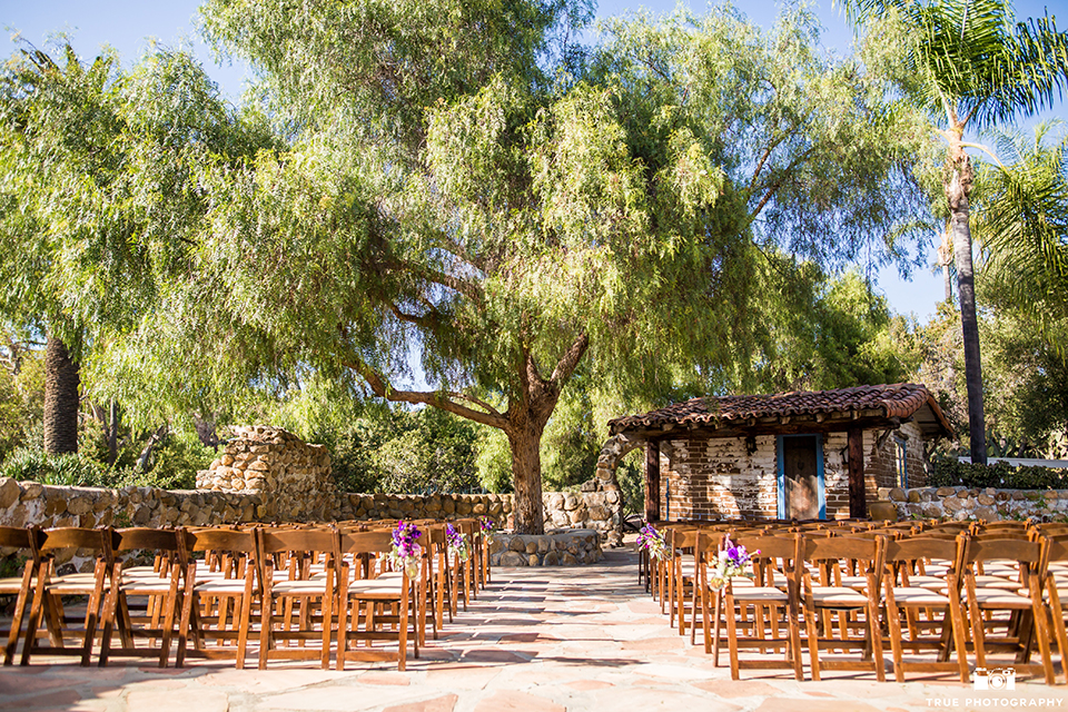 San diego outdoor wedding at leo carillo ranch ceremony set up outside with brown chairs and tree background with purple flower decor wedding photo idea for ceremony