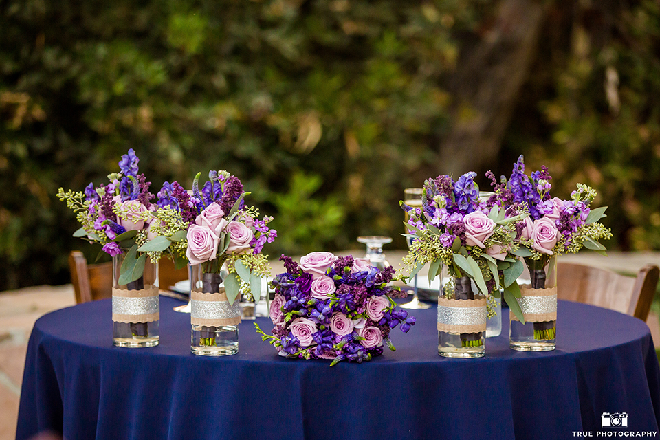 San diego outdoor wedding at leo carillo ranch reception table set up with purple linen and brown chairs with white place settings and light purple napkin decor with purple flower centerpiece decor 