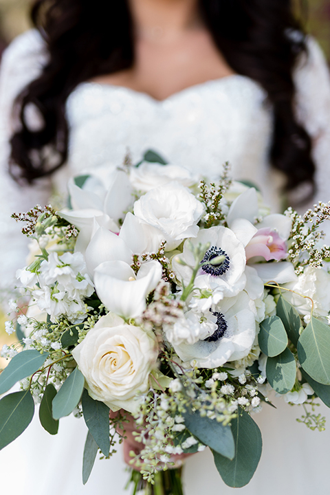 Temecula outdoor wedding at bella gardens estates bride lace ball gown with long sleeves and a sweetheart neckline with a tulle skirt holding white and green floral bridal bouquet close up