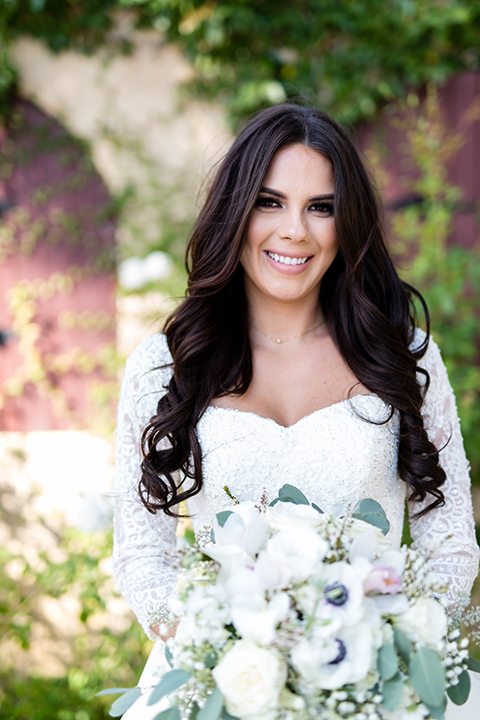 Temecula outdoor wedding at bella gardens estates bride lace ball gown with long sleeves and a sweetheart neckline with a tulle skirt holding white and green floral bridal bouquet