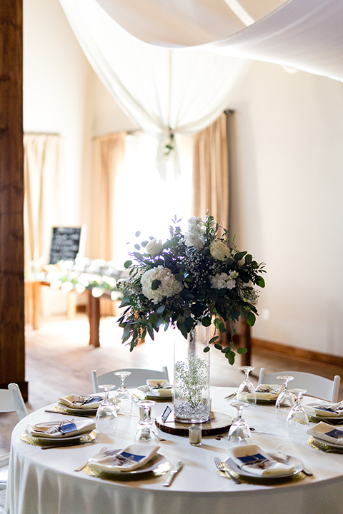 Temecula outdoor wedding at bella gardens estates wedding reception dessert table white linen with assortment of desserts with black and white sign and three tier white wedding cake with white flowers on top and pearl design 