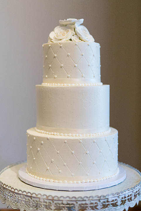 Temecula outdoor wedding at bella gardens estates wedding reception dessert table white linen with assortment of desserts with black and white sign and three tier white wedding cake with white flowers on top and pearl design 