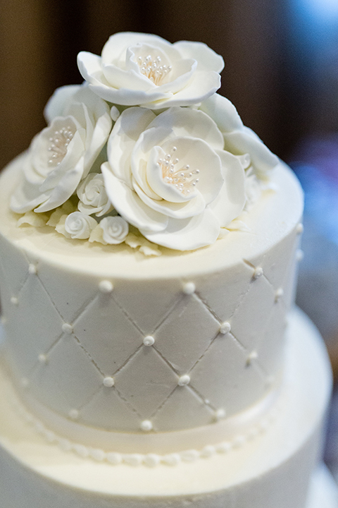 Temecula outdoor wedding at bella gardens estates wedding reception dessert table white linen with assortment of desserts with black and white sign and three tier white wedding cake with white flowers on top and pearl design 